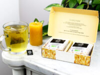 Coffret digestion de 12 infusettes ouvert sur une table en marbre avec une tasse qui infuse à coté
