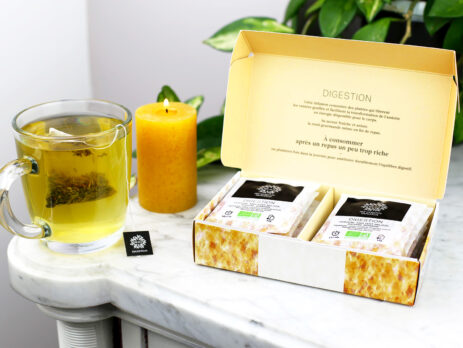 Coffret digestion de 12 infusettes ouvert sur une table en marbre avec une tasse qui infuse à coté