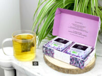 Coffret Sommeil 12 infusettes ouvert sur un meuble en marbre avec une tasse qui infuse à sa gauche